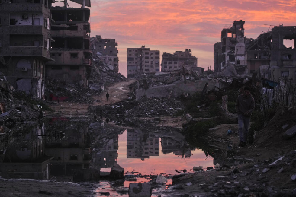 Palestinians walk amid buildings destroyed by Israeli air and ground operations in Gaza City.