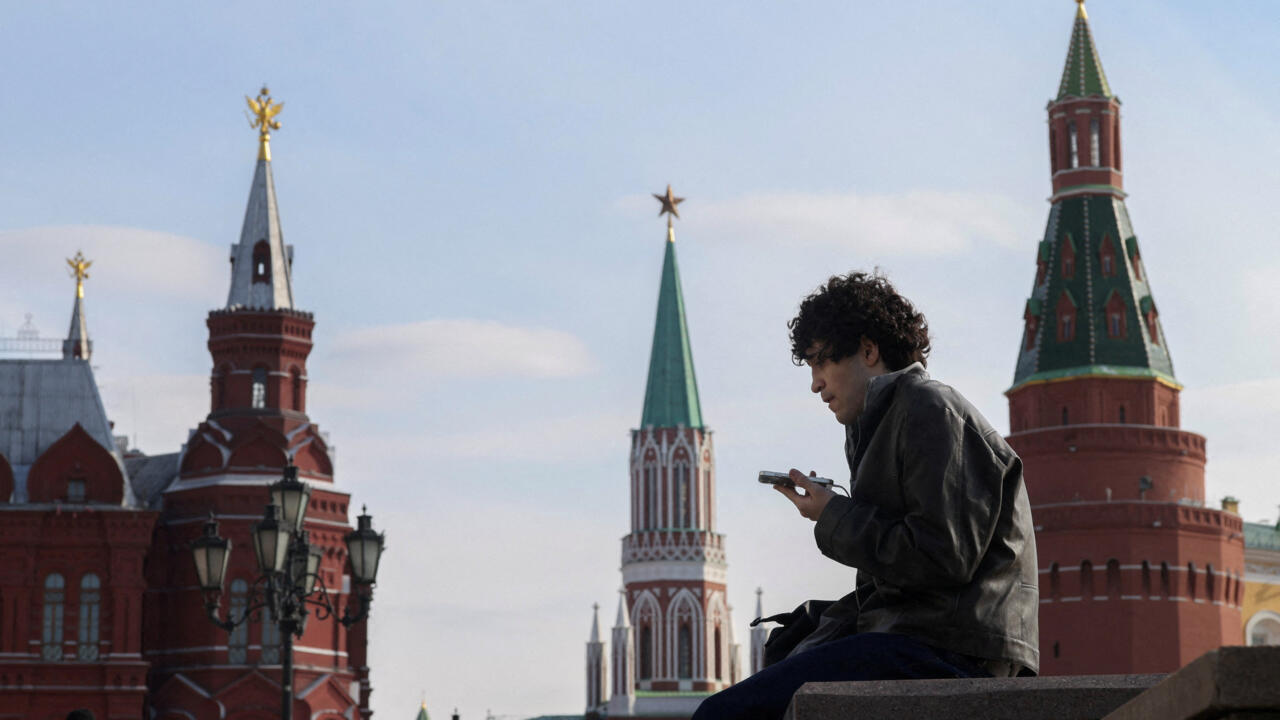 A delivery courier checks his mobile phone in central Moscow, on March 17, 2026