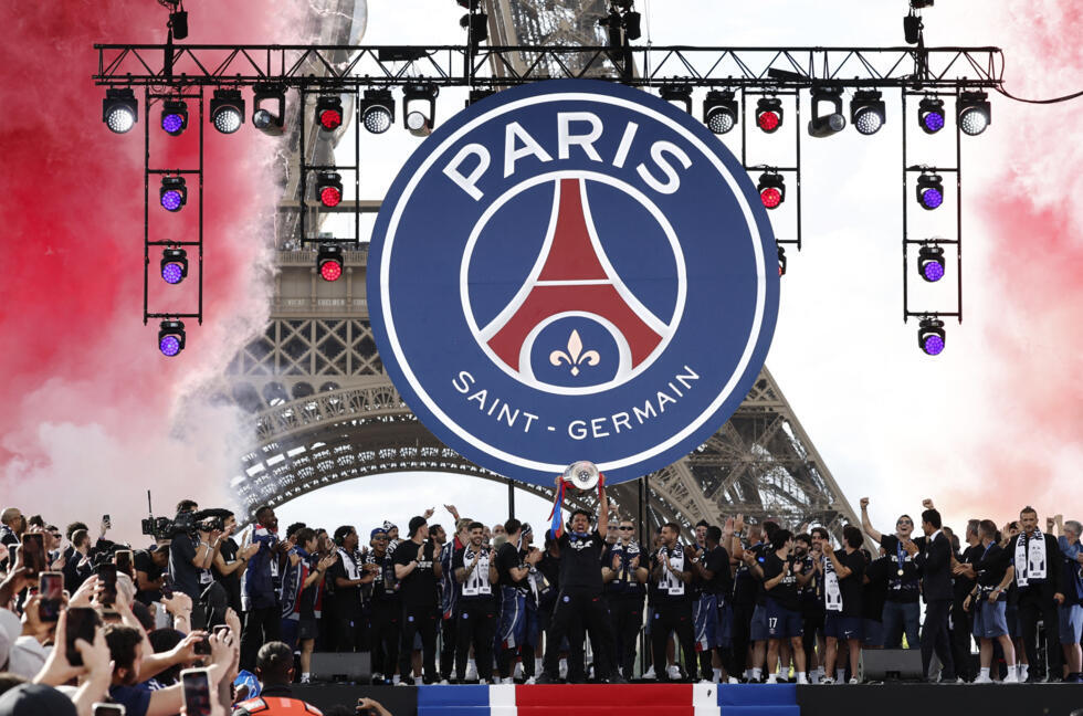 Paris St Germain's Marquinhos lifts the trophy as he celebrates with teammates after winning the UEFA Champions League.