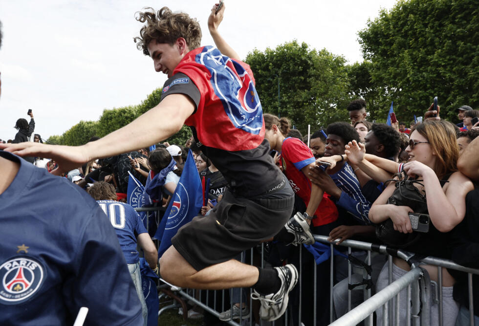 A PSG fan jumps over railing during celebrations at the Champs-de-Mars in Paris.