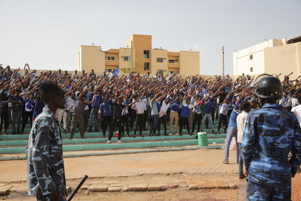 Soldiers stand guard while fans cheer the players during the Sudanese Premier League football match between Al Merrikh and Al-Hilal at the Khartoum Stadium in Sudan on June 10, 2026