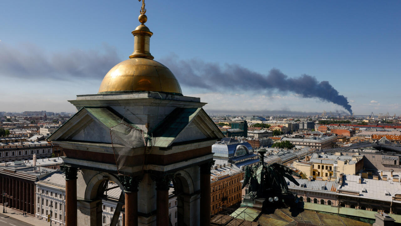 Cars are seen parked near banners with branding for the St. Petersburg International Economic Forum (SPIEF) at the forum