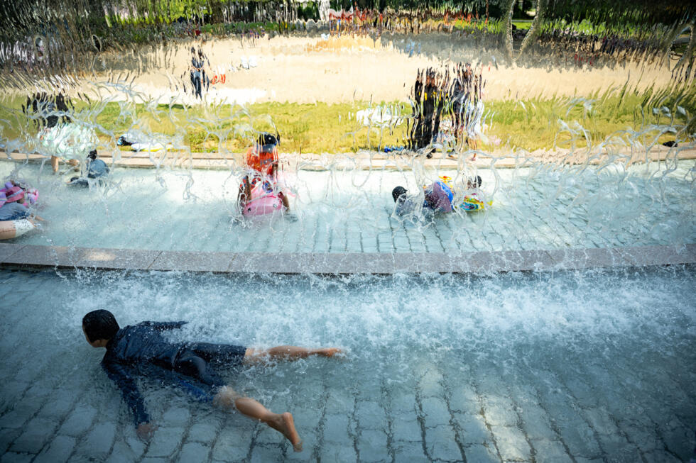 Children cool off in a public water playground at a park in Edogawa district of Tokyo on July 23, 2026, during a heatwave.