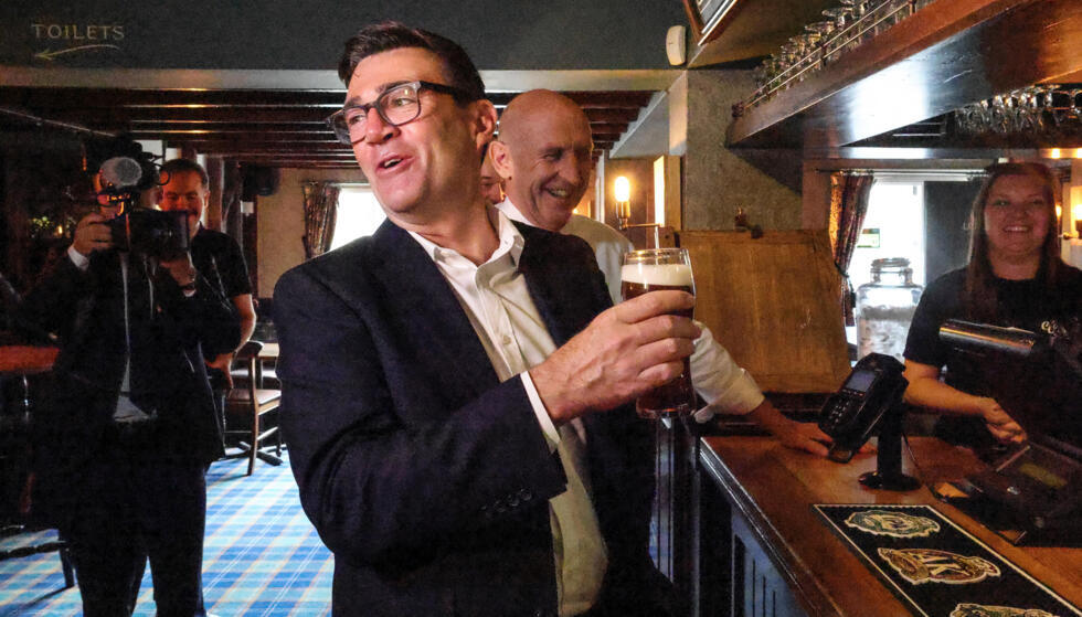 Britain's Prime Minister Andy Burnham holds a pint of beer during a visit to the Hare Inn in Harlow, east of London.