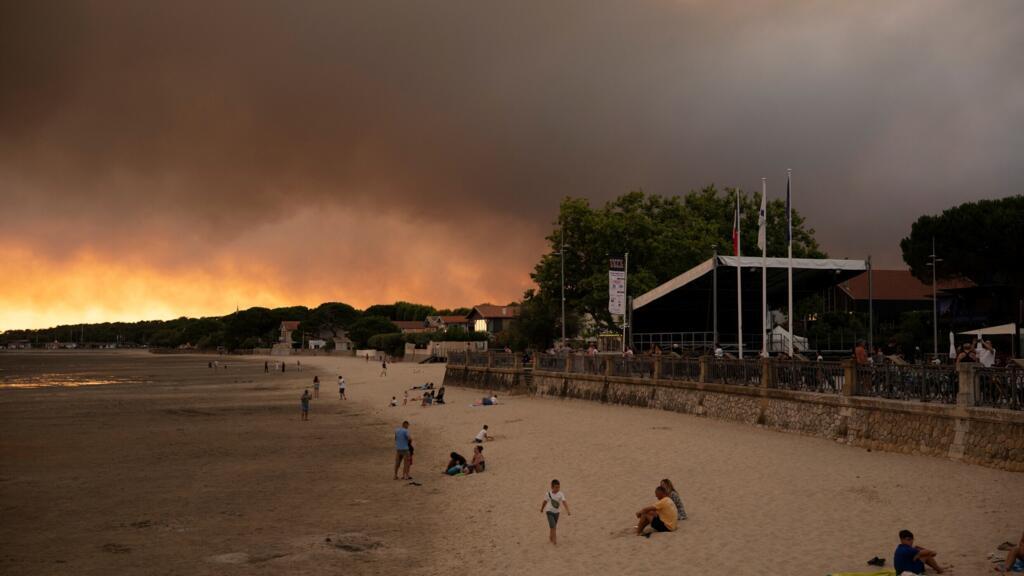 This picture shows people on the beach in Andernos-Les Bains during fire in Lege Cap-Ferret forest, southwestern France on July 23, 2026, as part of the nearby area has been evacuated.