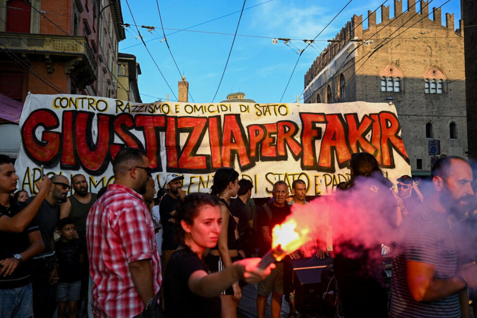 A protester holds a flare in front of a banner reading in Italian "Justice for Fakir" during a protest following the death of Abderrahim Fakir in Bologna, Italy