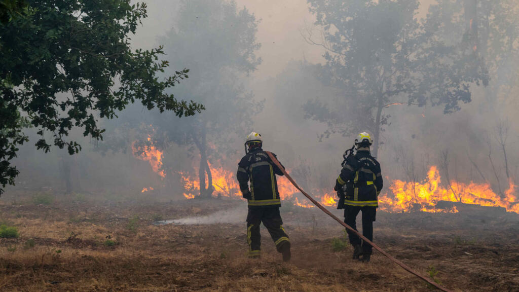 Fiirefighters spray water in a burning forest in the Lège-Cap-Ferret region, western France, Friday, July 24, 2026.