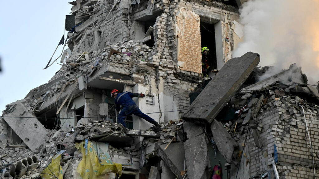 Des secouristes ukrainiens à la recherche de survivants dans les décombres d'un immeuble frappé par une attaque russe, le 2 juillet 2026, à Kiev.