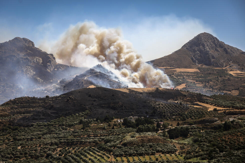 This photograph shows an area ablaze during a forest fire near the village of Asomatos, on the Greek island of Crete, on July 30, 2026. Two firefighters died on Wednesday while battling the wildfire