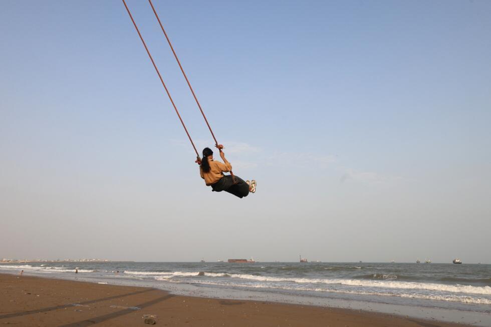 An Iranian enjoys a swing erected along the seashore, as vessels are seen in the Strait of Hormuz off the port city of Bandar Abbas, in southern Iran 