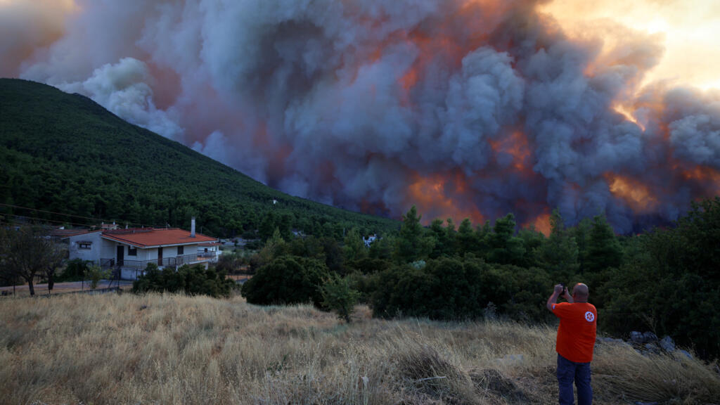 Un hombre graba imágenes de un incendio forestal mientras el humo se eleva sobre Krio Pigadi, Grecia, el 1 de agosto de 2026.