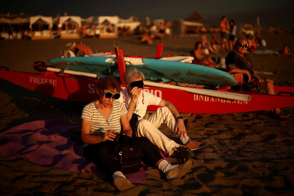 Beachgoers watch a solar eclipse as the moon partially covers the sun and briefly dims the afternoon light along the coast of Fregene, near Rome, August 12, 2026