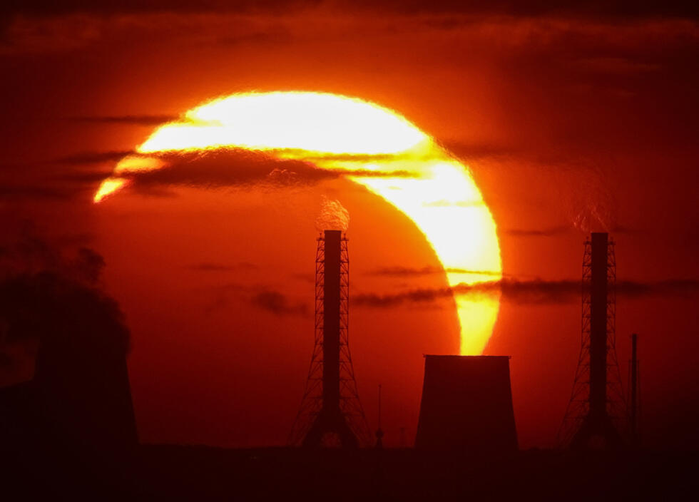 A thermal power plant is silhouetted during a partial solar eclipse in St. Petersburg, Russia, on August 12, 2026.