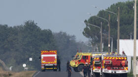 Firefighters stand near the scene where two firefighters died while battling a building fire in Merignac.