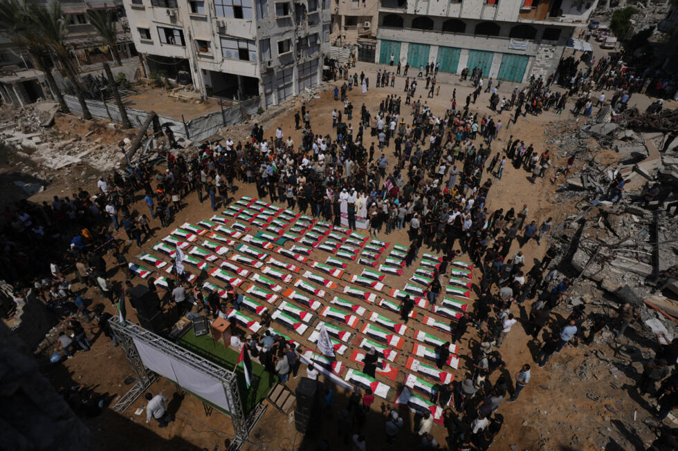 Des personnes en deuil se rassemblent autour des dépouilles, recouvertes du drapeau national, des membres des familles Hassayna et Abu Sharia, tués lors d'une frappe israélienne en 2023.