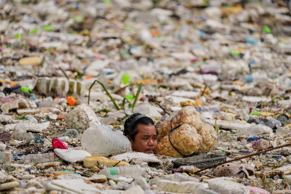 A worker uses improvised floats while trying to clear a sea of garbage and debris brought by intense monsoon rains at the Redemptorist Water Channel in Paranaque city, Metro Manila, Philippines.