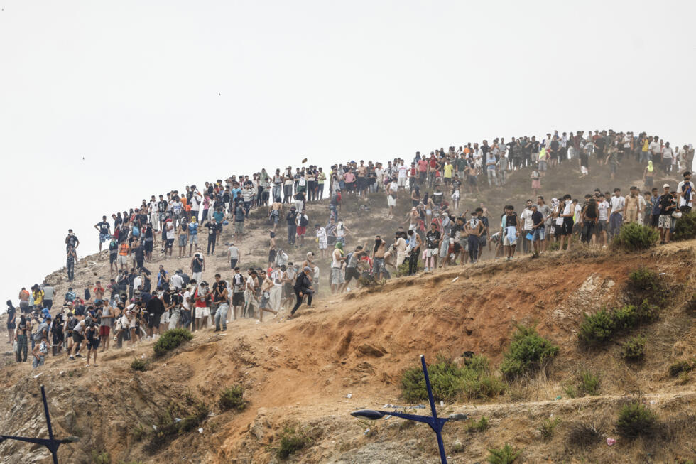 Migrants attempting to cross into Spain's North African enclave of Ceuta gather on a hilltop during clashes with Moroccan security forces near the town of Fnideq on the Morocco-Spain border