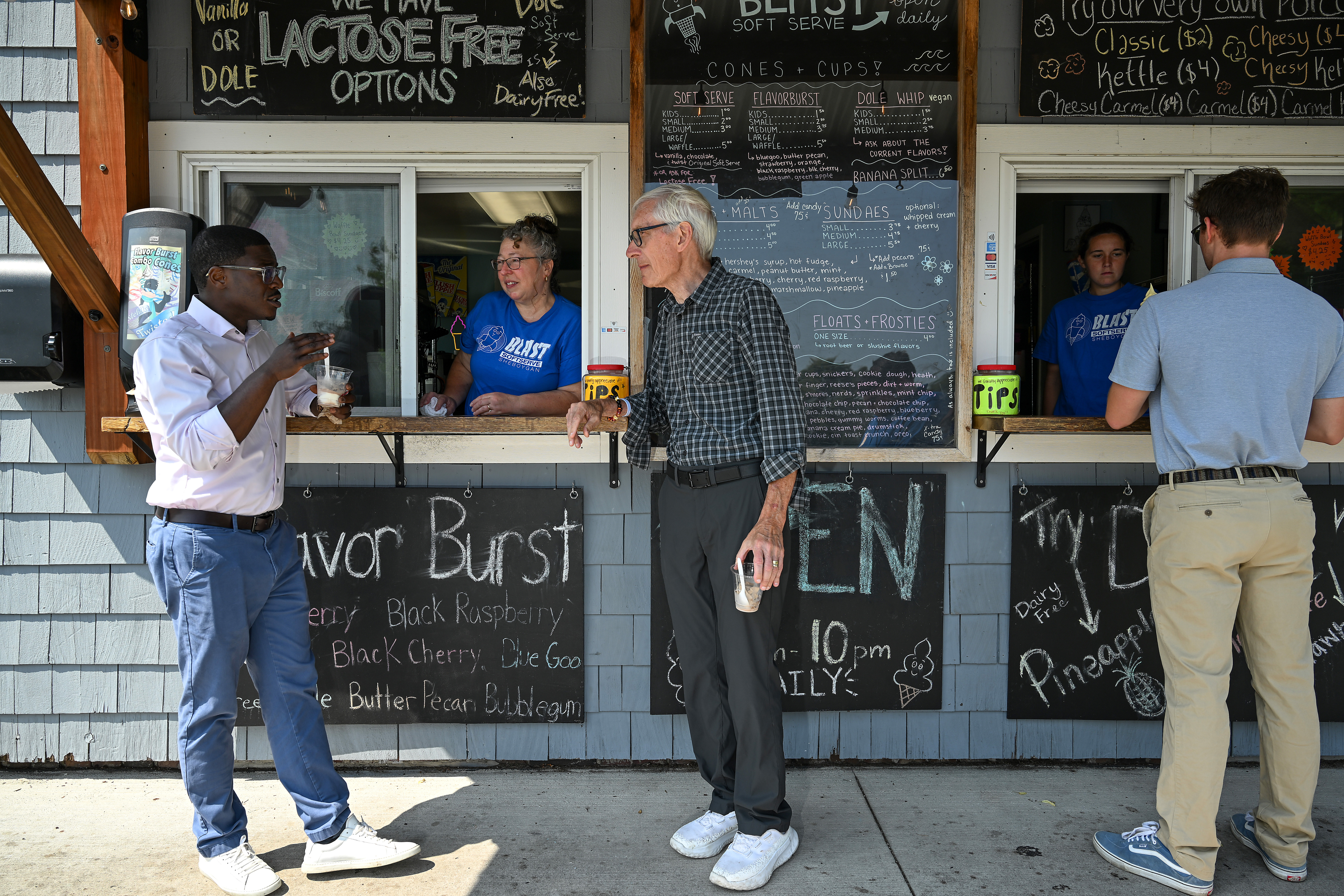 Wisconsin gubernatorial candidate David Crowley, left, speaks with Blast Soft Serve ice cream shop owner Jamie Evans, center, and Wisconsin Gov. Tony Evers during a campaign stop in Sheboygan, Wisconsin, on Aug. 7, 2026.